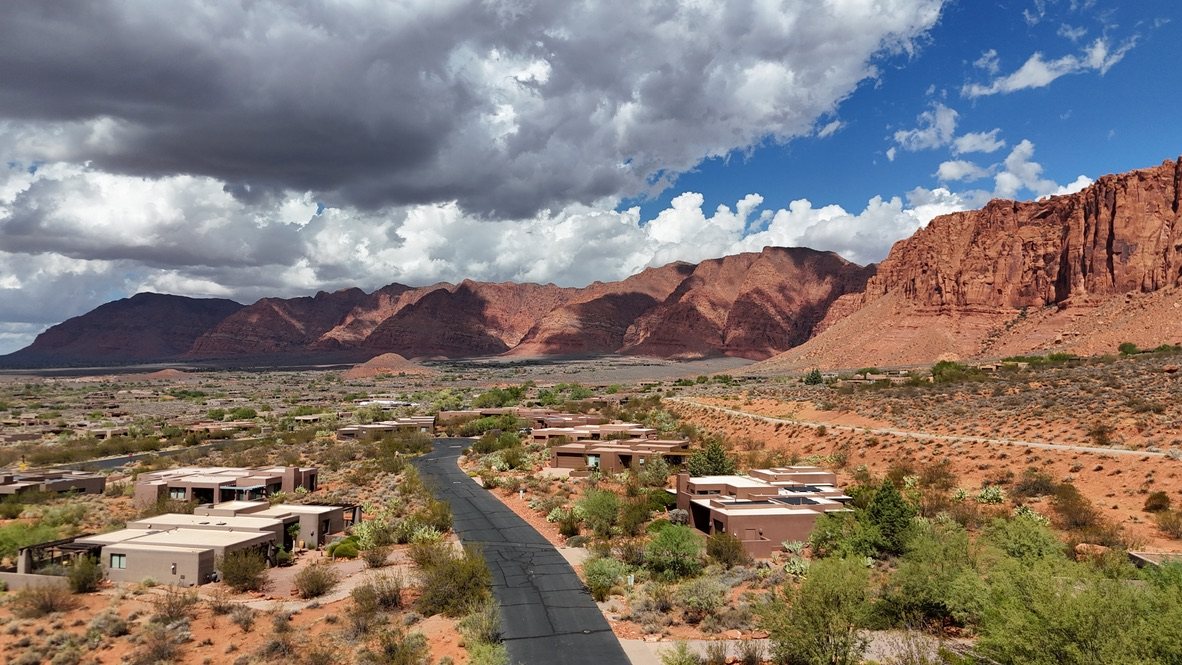 Aerial view of desert homes in Kayenta below red cliffs in Ivins, Utah